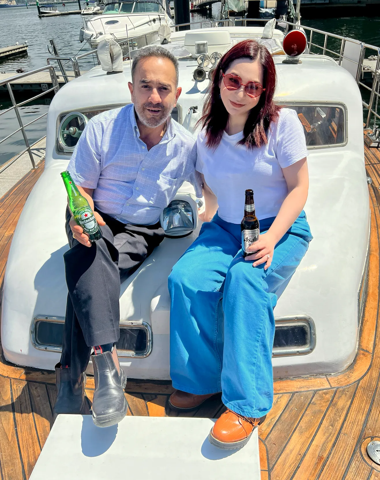 A couple seated with drinks on Elizabeth Anne's white bow at the marina