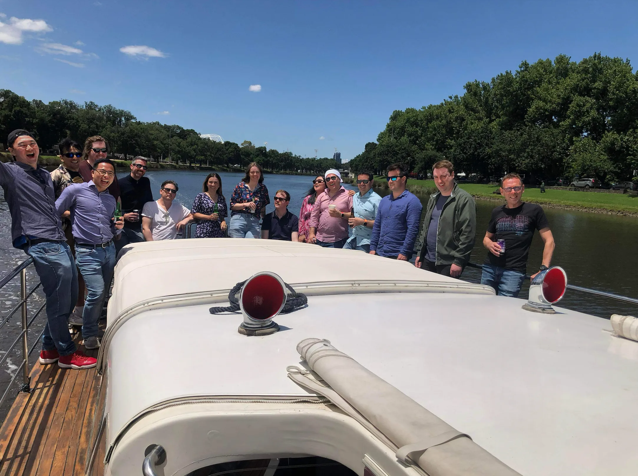 A dressed-up group of guests along the side deck of Elizabeth Anne, cruising the tree-lined Yarra