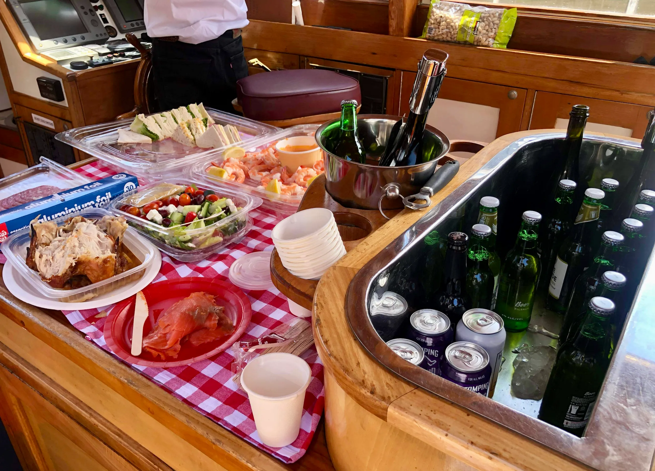 A relaxed catering spread on the wheelhouse bench, laid on a gingham cloth